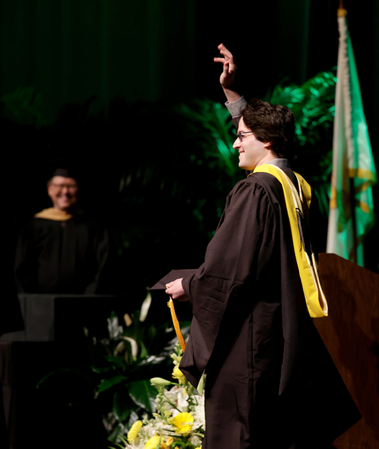 Jose Schneider, who earned his Master of Science in Medical Physics, waves to the audience as he accepts his diploma.