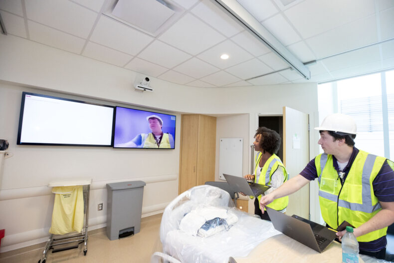 HealthIT team members perform final checks of the two-way video system in patient rooms before the floor opens. (photo by Susan Urmy)