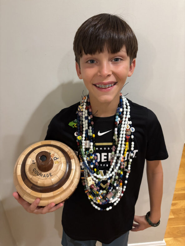 Patient Sam Hatch, 11, with his 684 beads around his neck. He is holding the wooden container he keeps his stand of beads in.