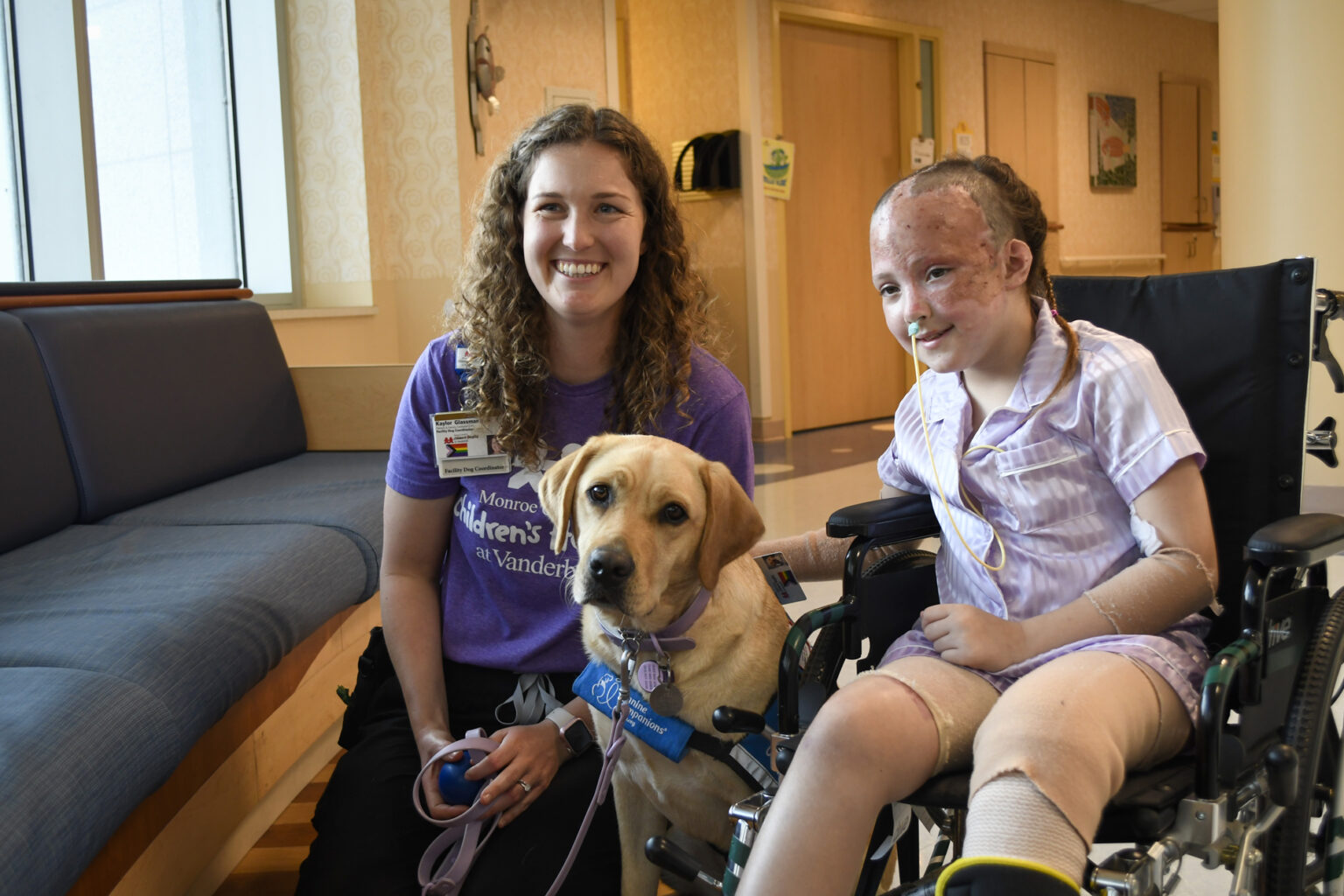 Patient Brynlee Pruitt with facility dog Velour and handler, Kaylor Glassman, MS.
