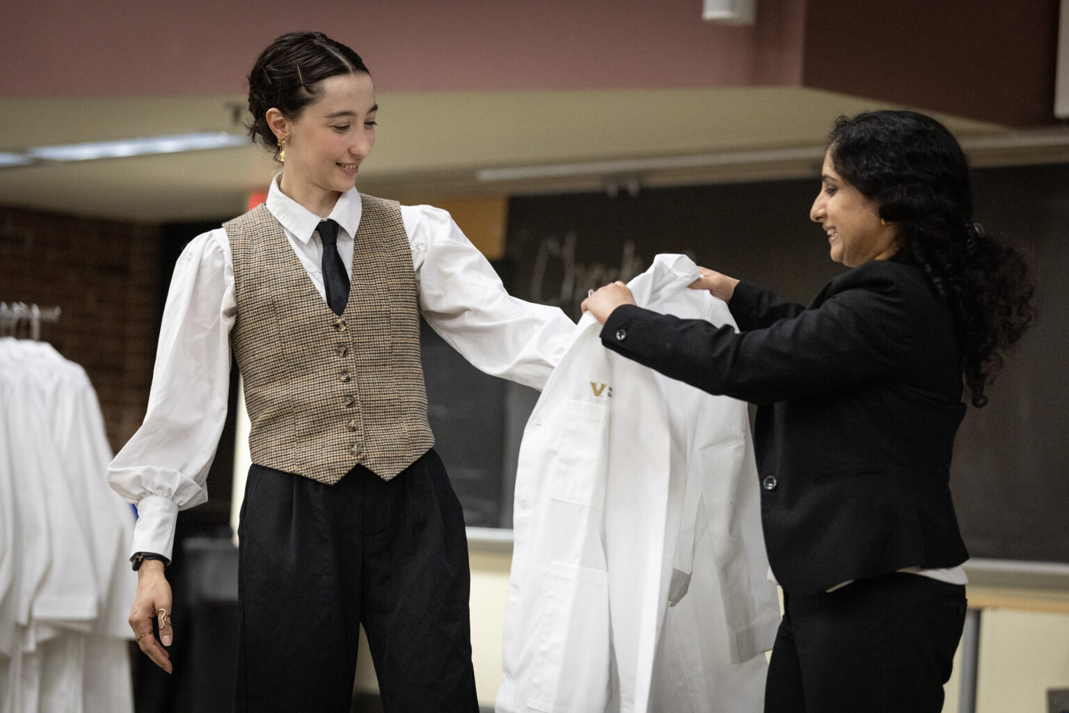 Nal Barcik Weissman, from Southern California, admitted to the Interdisciplinary Graduate Pathway, receives her white coat from IGP Director Madhvi Venkatesh, DPhil, Assistant Professor of Biochemistry. (photo by Erin O. Smith)