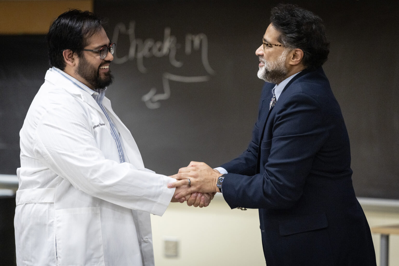 Cydney Parmar, from Tallahassee, Florida, admitted to the Epidemiology PhD program, shakes hands with program Director Peter Rebeiro, PhD, MHS, Associate Professor of Medicine, after receiving his white coat. (photo by Erin O. Smith)