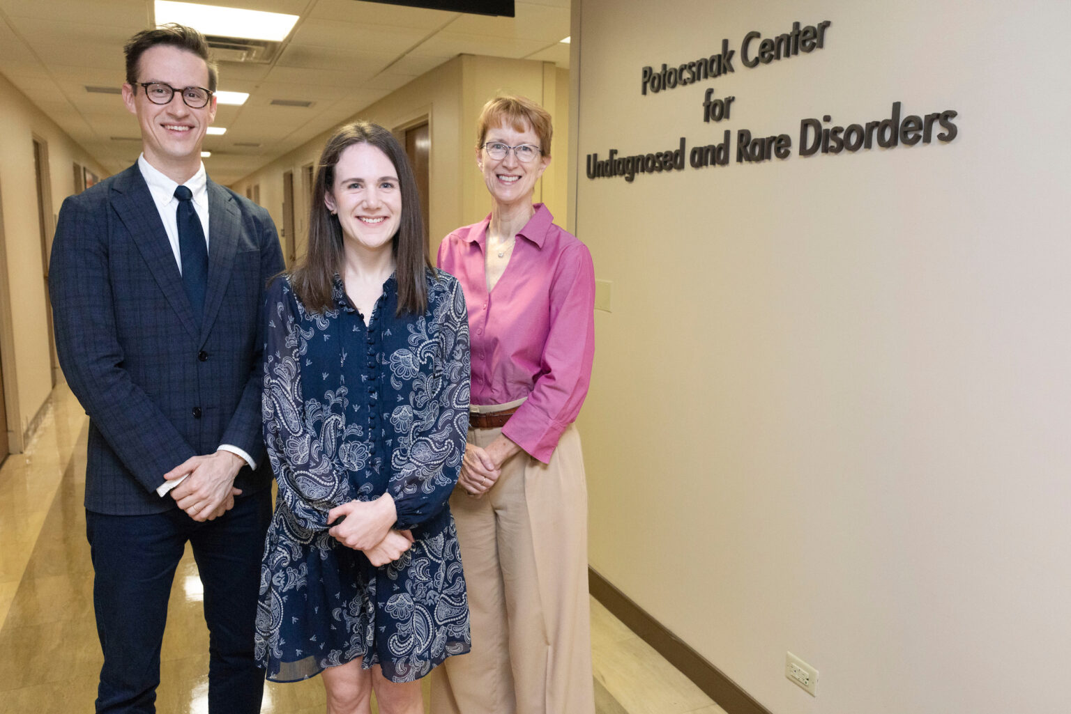 Kevin Byram, MD, Erica Gray, MD, and Saralyn Williams, MD, pose in a hallway beside a sign reading “Potoschnak Center for Undiagnosed and Rare Disorders.”