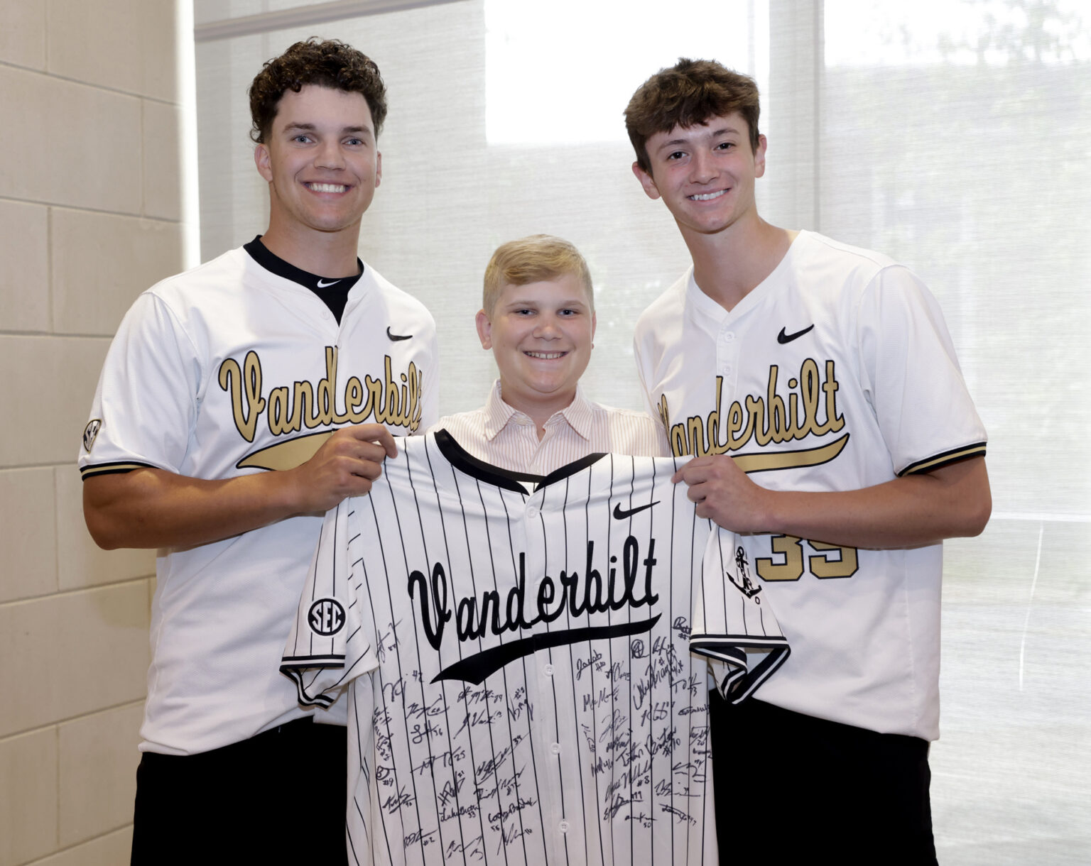 Cancer patient Easton Reeder, center, was given a jersey signed by the Vanderbilt Commodore baseball team, including pitchers Cody Bowker, left, and Connor Fennell. (photo by Donn Jones)