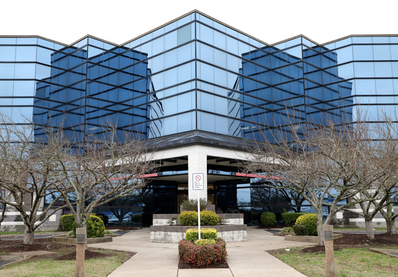 Blue-glass Vanderbilt Wilson County Hospital facility with a covered entrance, leafless trees, landscaped beds, and a no-smoking sign in front.