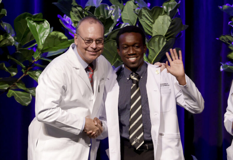 First-year medical student Tristan Sealy of Katy, Texas, waves to the crowd after receiving his white coat from Jeff Balser, MD, PhD. (photo by Donn Jones)