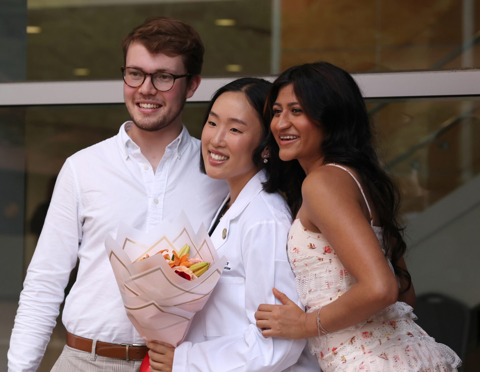 Scott Hibbard, Yuna Chung and Priyal Patel, left to right, pose for photos after Chung received her white coat.
