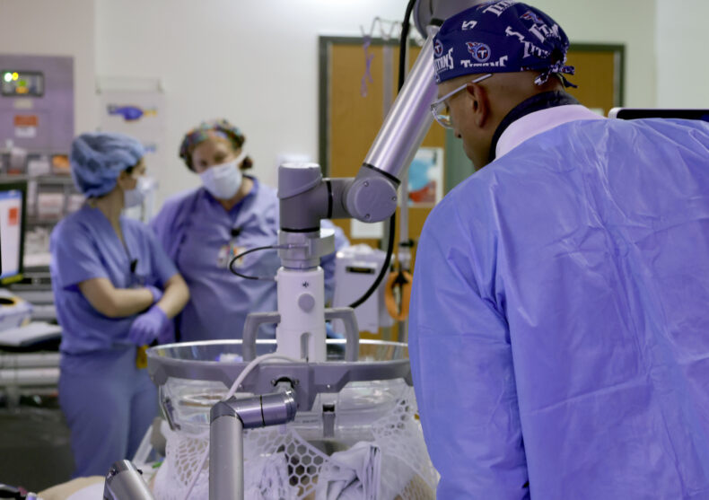 Sekhar Padmanabhan, MD, positions the arm of the device used to pass ultrasound waves into the patient's abdomen to liquefy liver tumors. (photo by Donn Jones)