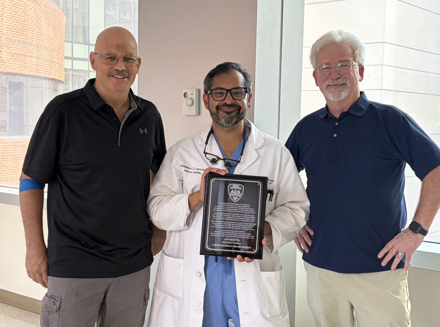 Ashish Shah, MD, center, holds a plaque of appreciation from the North Patchogue Fire Department in Long Island, New York. Bob Meyer, left, is a volunteer firefighter for the department who received a heart transplant at the Vanderbilt Transplant Center, performed by Shah. Jim Hawley, BSN, RN, right, is a former Vanderbilt nurse who made his old friend, Meyer, aware of the Vanderbilt Transplant Center.